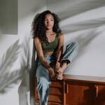 Beautiful woman sitting on a cabinet in sunlight with plant shadows.