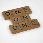 Scrabble letter tiles arranged to spell 'ONE' in a crossword style on a white background.